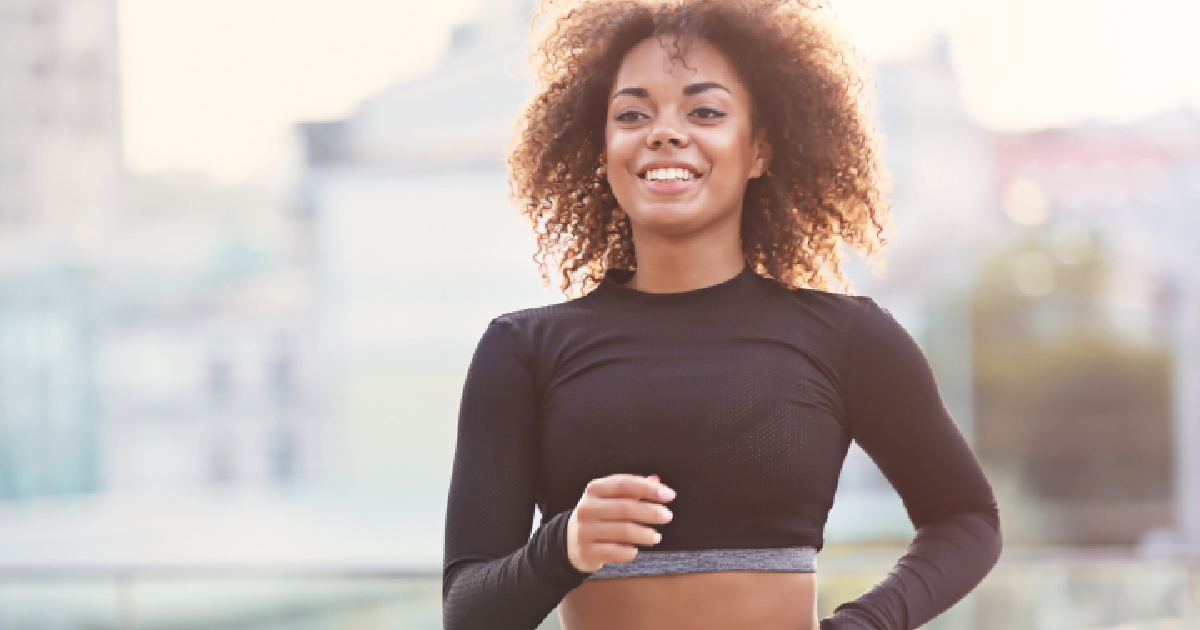 Smiling young woman jogging outdoors, representing active recovery by PRP therapy in San Carlos, CA.